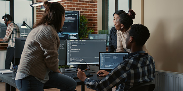 Students sitting at computer with code on the screen.